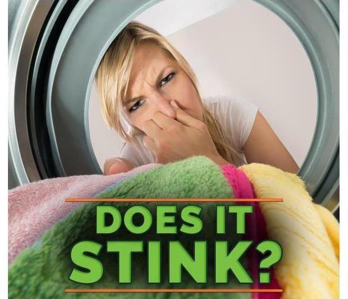 woman covering her nose when opening the door of her washing machine