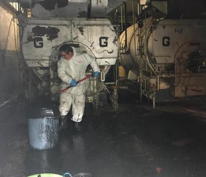 A technician wearing protective gear while cleaning a flooded building