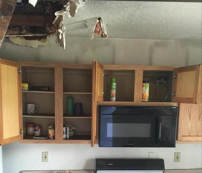 Kitchen cabinet doors open, hole on ceiling 